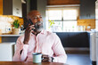 © Wavebreak Media - Smiling african american senior man holding coffee mug talking over smartphone in log cabin