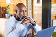 © Wavebreak Media - Serious bald african american senior man with hands clasped looking at laptop in log cabin