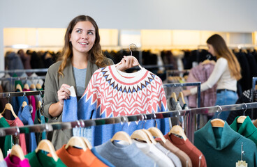 Wall Mural - Portrait of young female shopper with winter sweater in showroom