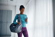 © Drazen - African American athletic woman using smart phone in locker room at gym.