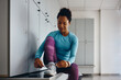 © Drazen - Happy black athlete preparing for sports training and tying her shoelace in dressing room at gym.