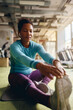 © Drazen - Black female athlete stretching while warming up for sports training in gym.