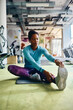© Drazen - African American athletic woman stretching her leg while working out in gym.