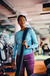 © Drazen - African American athletic woman with battle ropes in gym looking away.