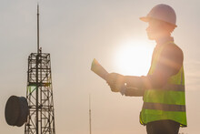 Engineer Manager Worker Working Outdoors With Telecommunication Antenna And Sunset Background.
