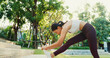 © tirachard - Beautiful young Asia athlete lady exercises stretching her body warm up after running in urban park environment in evening sunset. Outside workout and fitness healthy lifestyle concept.