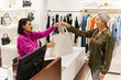 © Seventyfour - Smiling woman handing bag with clothes to customer in boutique
