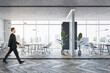 © Who is Danny - Side view of young businessman walking in modern glass office interior with wooden flooring, furniture, window with city view and other objects.