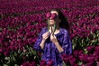 © Milou Dirks - portrait of happy woman holding tulips in front of her  eyes in dutch field of purple flowers in spring