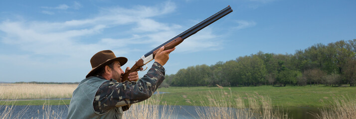 Wall Mural - Hunter man in camouflage with a gun during the hunt in search of wild birds or game.