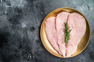 Uncooked Raw chicken chop breast fillets on a plate, poultry meat. Black background. Top view. Copy space