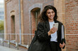 © Drobot Dean - Young brunette businesswoman using cellphone while walking outdoors