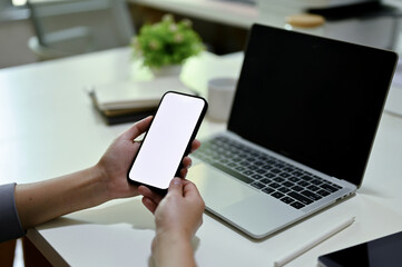 Close-up image of a female offie worker using her smartphone at her office desk.