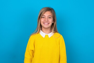 Wall Mural - caucasian teen girl wearing yellow sweater over blue studio background with a happy and cool smile on face. Lucky person.