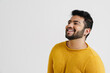 Cheerful indian guy looking aside while posing isolated over white wall