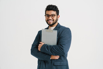 Wall Mural - Young indian man holding clipboard isolated over white wall