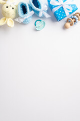 Wall Mural - Baby accessories concept. Top view vertical photo of blue knitted booties giftbox with bow bunny toy wooden rattle and pacifier on isolated white background with copyspace