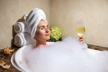 Woman Relaxing In Bath Full Of Foam With Glass Of Champagne In SPA Hotel