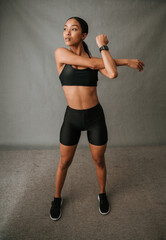 Multi Ethnic woman standing and very focused doing her arm stretching exercises.