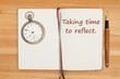 Taking time to reflect message on a journal with pocket watch and pen on wood desk