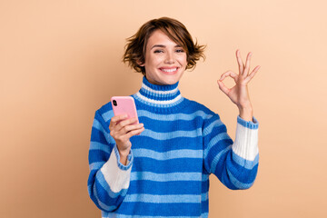 Portrait of influencer blogger girl promoter recommend new app for remote chatting without wifi okey symbol isolated on beige color background