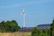 photovoltaic panels on the roof of farm buildings with wind turbine in the background