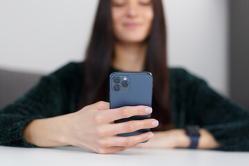 Young woman typing a message with modern smart phone app. Brunette female person texting online with a mobile phone