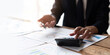 © Natee Meepian - Close up Business man using calculator and laptop for do math finance on wooden desk in office and business working background, tax, accounting, statistics and analytic research concept