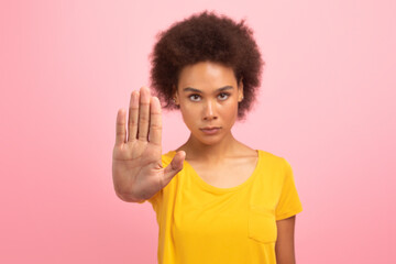 Serious confident young african american woman in yellow t-shirt make stop sign with hand