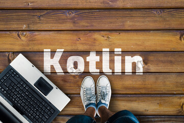 Wall Mural - kotlin mobile application programming language. legs in shoes standing next to laptop and word kotli
