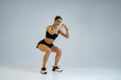 © Yaroslav Astakhov - Fitness woman doing deep squat exercise on studio background. Workout Concept. High quality photo