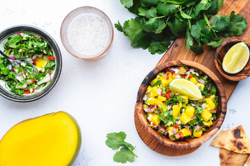 Wall Mural - Spicy mango salsa sauce with red chili peppers, onion, garlic, lime and cilantro, white table background, top view