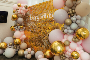 A large festive photo zone for a birthday, decorated with gold sequins, pink, gray and gold balloons of different sizes. Celebrating concept