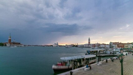 Wall Mural - Basilica Santa Maria della Salute, Cathedral of San Giorgio Maggiore during sunset timelapse, Venice, Italy. San Marco campanile on background. Orange cloudy sky. Boats and ship on Grand Canal