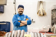 A smiling middle-aged fishmonger poses with his arms crossed behind the sales counter, selling food, small and medium business concept.