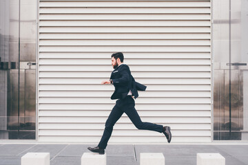 Energetic young bearded professional businessman jumping in mid-air