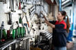 © Siam Stock - Selective focus of various car repair tools, screwdrivers, hanging on the wall and keep in toolholders in a garage with a blurred on right side of Asian female mechanic in uniform hanging tool on wall