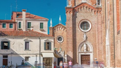 Wall Mural - Entrance to Basilica di Santa Maria Gloriosa dei Frari timelapse and narrow street. This old famous church was built in the 14th century and is a tourist attraction. Blue sky at summet day. Venice