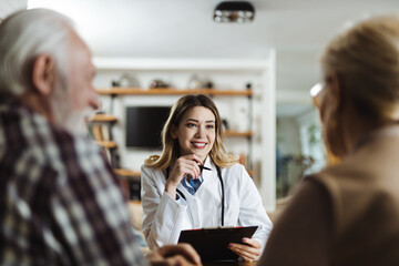 Wall Mural - Happy female nurse talking with her patients during a home visit