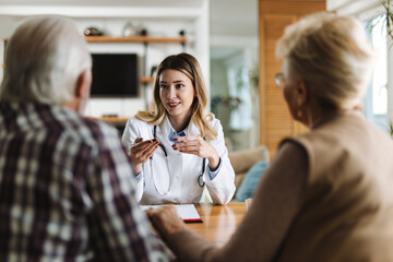 Happy female nurse talking with her patients during a home visit