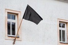 A Black Flag Hanging Under The Window On The Facade Of The Building