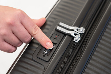 selecting the numbers on the combination lock of the suitcase with your finger to open it