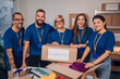 © Zamrznuti tonovi - Diverse volunteers working in a charity donation center and packing clothes and food