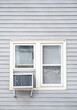 © Eric Skadson - An exterior view of a pair of windows with an air conditioner and two faded American flags