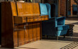Stare pianino i niebieski fotel ( oraz stołek ze skrzynki po owocach) stoją na podłodze z ceramicznych płytek .