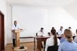 © New Africa - Senior doctor giving lecture in conference room with projection screen