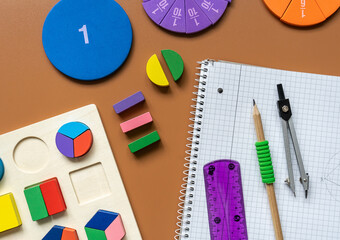 Fractions, rulers, pencils, notepad on brown background. Set of supplies for mathematics and for school.  Back to school, fun education concept	