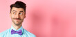 Close-up of handsome smiling guy with moustache, looking left at logo with pleased face, standing on pink background