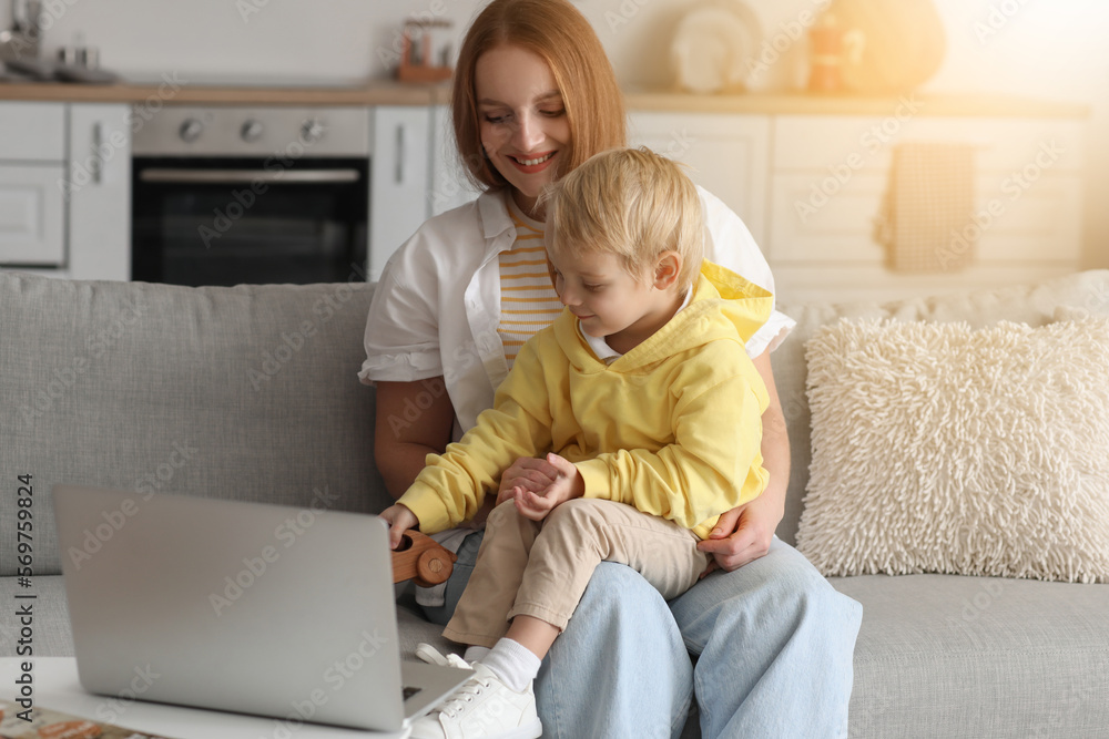 Mother with her little son watching cartoons at home