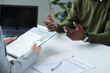© AnnaStills - Close-up of young woman interviewing man at table during job interview, she reading resume and asking questions